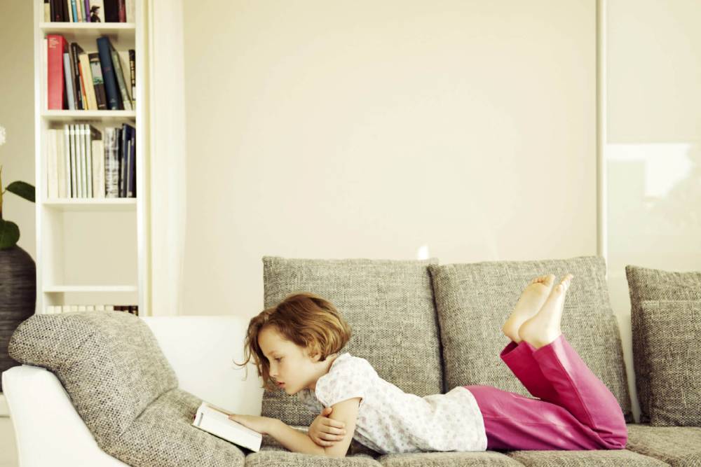 A girl lying on sofa and reading book